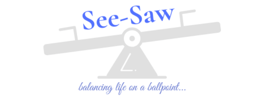 Blog logo: a see-saw sitting on a central column shaped like a pen nib, the title 'See-Saw' above the image and the tagline 'balancing life on a ballpoint' below it, both in indigo colour font.