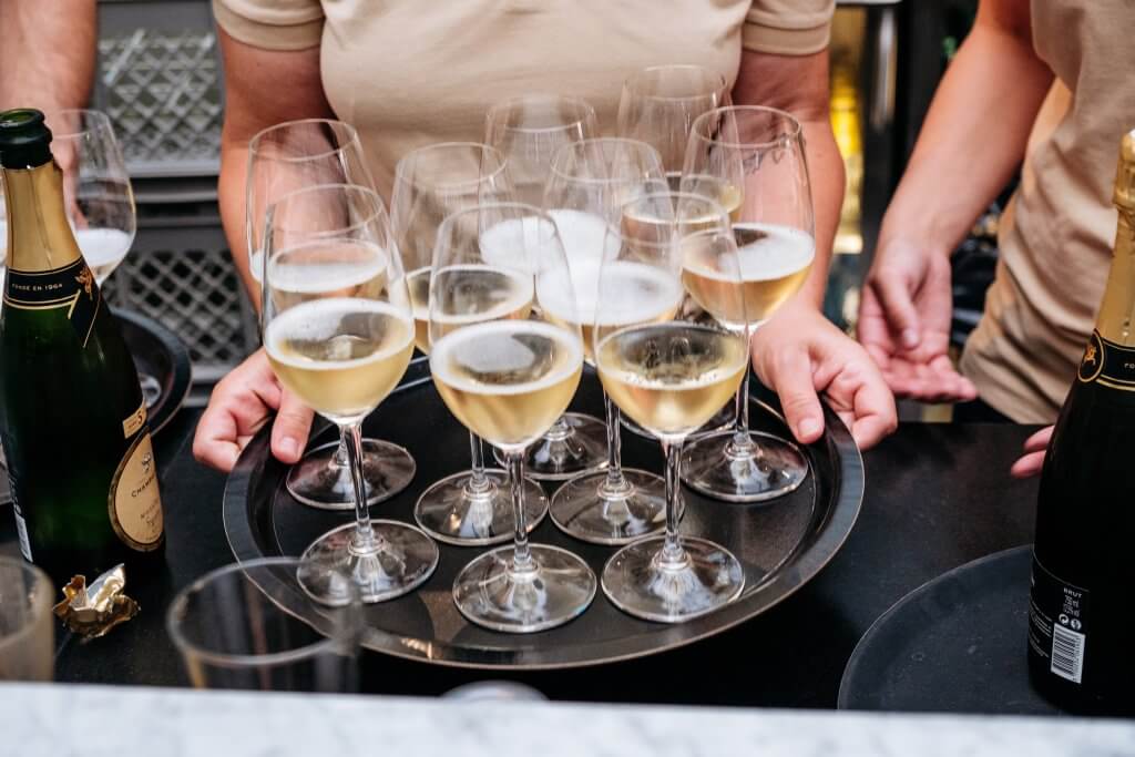 A waitress holding a tray of glasses of prosecco.