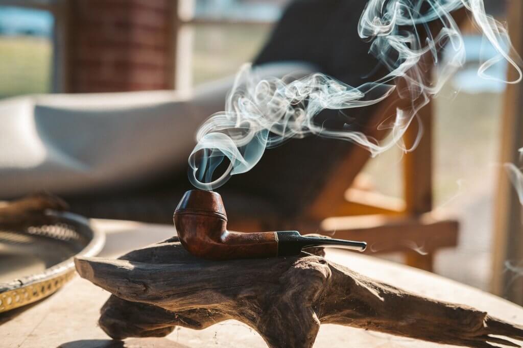 Smoke coils up from a tobacco pipe lying in the sun.