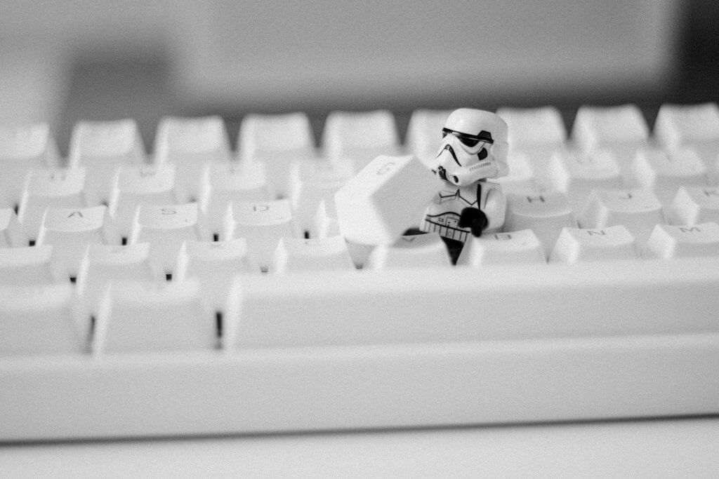 A miniature stormtrooper toy breaking out of a keyboard.